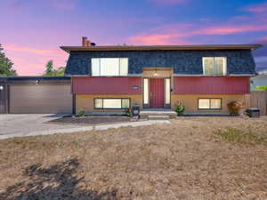 Bi-level home with brick siding, a garage, mansard roof, concrete driveway, and a shingled roof