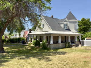 View of front of home featuring a front yard, stone siding, a chimney, roof with shingles, and covered porch
