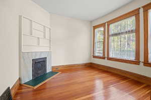 Unfurnished living room featuring hardwood / wood-style flooring and a high end fireplace