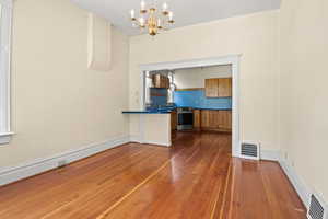 Unfurnished dining area with a chandelier and hardwood / wood-style floors