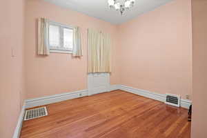 Empty room featuring a chandelier and hardwood / wood-style floors