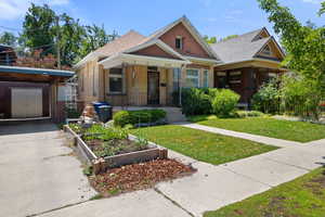 View of front of home with a garden, a front lawn, brick siding, covered porch, and concrete driveway