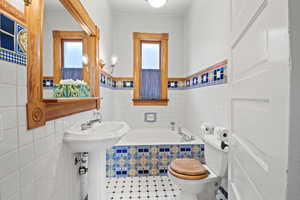 Full bathroom featuring plenty of natural light, tile walls, a garden tub, wainscoting, and tile patterned flooring