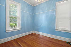 Unfurnished room featuring a chandelier, crown molding, and hardwood / wood-style floors