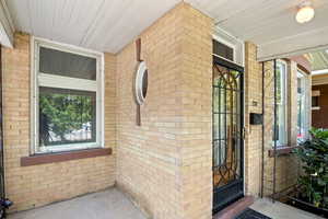 Property entrance featuring brick siding and a porch