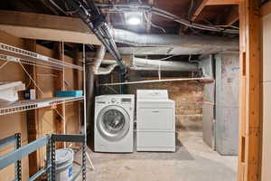 Unfinished below grade area featuring separate washer and dryer
