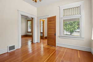 Empty room with a chandelier and hardwood / wood-style flooring