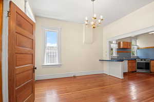 Kitchen with stainless steel electric range, wood-type flooring, white dishwasher, a chandelier, and dark countertops