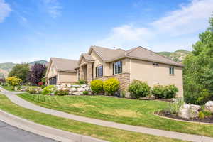 View of home's exterior featuring stucco siding, a mountain view, stone siding, and a yard