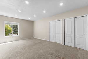 Unfurnished bedroom featuring recessed lighting, carpet, and two closets