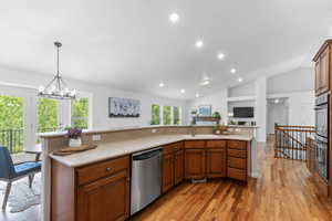 Kitchen with stainless steel appliances, light countertops, light wood-type flooring, lofted ceiling, and recessed lighting
