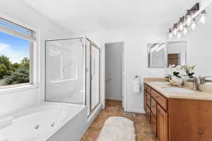 Full bath with a stall shower, double vanity, plenty of natural light, and a jetted tub