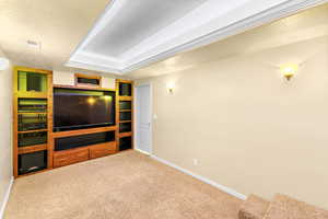 Unfurnished living room with carpet flooring and a raised ceiling