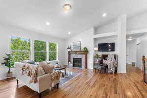Living area with lofted ceiling, light wood-style floors, a fireplace, and recessed lighting