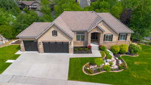 View of front of property with stucco siding, stone siding, a tiled roof, and a garage