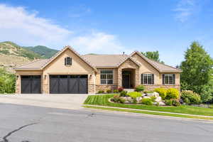 View of front facade featuring stucco siding, stone siding, an attached garage, driveway, and a mountain view