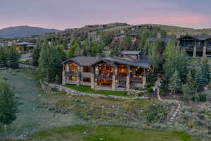 Back of property at dusk featuring a chimney, a mountain view, and a balcony