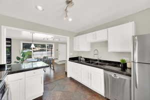 Kitchen featuring appliances with stainless steel finishes, rail lighting, and white cabinets