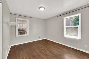 Spare room with dark wood-style flooring and baseboards
