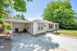 View of front of property with concrete driveway, an attached carport, and a chimney