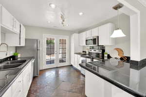 Kitchen with appliances with stainless steel finishes, french doors, recessed lighting, white cabinets, and stone tile flooring