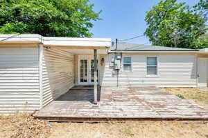Back of property featuring a deck, a shingled roof, and french doors