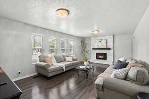Living room with a textured ceiling, wood finished floors, and a fireplace