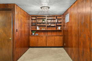 Hallway with wood walls, carpet floors, a textured ceiling, and a chandelier