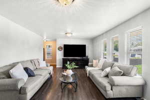 Living area featuring a textured ceiling and dark wood finished floors