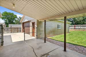 View of patio with an attached garage and a gate