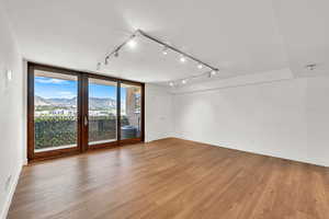 Empty room with rail lighting, a mountain view, and light wood-style flooring