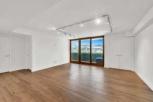 Unfurnished room featuring rail lighting, wood finished floors, and floor to ceiling windows