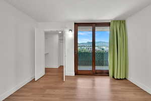 Unfurnished bedroom with a mountain view, light wood-style floors, access to outside, and a walk in closet