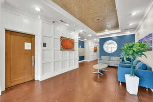 Tiled living area featuring a raised ceiling, crown molding, and recessed lighting