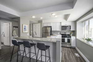 Kitchen with stainless steel appliances, dark wood finished floors, and a kitchen bar