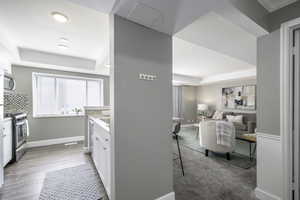 Kitchen featuring stainless steel appliances, a raised ceiling, white cabinetry, and light countertops