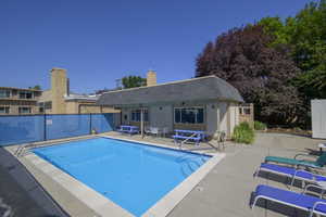 Community pool featuring a patio, a storage structure, and an outbuilding