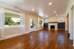Upstairs living room featuring original hardwood floors, a fireplace with flush hearth, recessed lighting, and crown molding