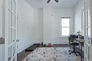 Office area with dark wood-style flooring, a ceiling fan, and french doors