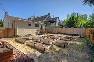 Back of property with stucco siding, a vegetable garden, and a fenced backyard