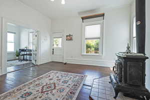 Foyer with wood-type flooring, crown molding, and a wood stove