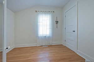 Unfurnished room with light wood-style flooring and lofted ceiling