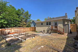 Rear view of house featuring stucco siding, a vegetable garden, and a chimney