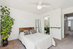 Carpeted bedroom featuring ensuite bath and a ceiling fan