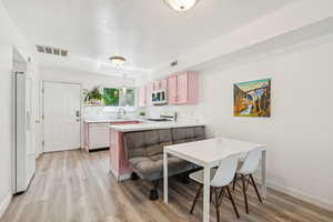 Kitchen featuring white appliances, a peninsula, light wood finished floors, and light countertops