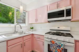 Kitchen featuring white appliances, light countertops, and decorative light fixtures