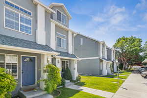 View of front facade featuring stucco siding, a front yard, and a residential view