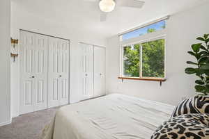 Carpeted bedroom featuring two closets and ceiling fan