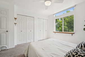 Carpeted bedroom featuring multiple closets and ceiling fan