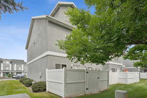 View of side of home with stucco siding and a gate